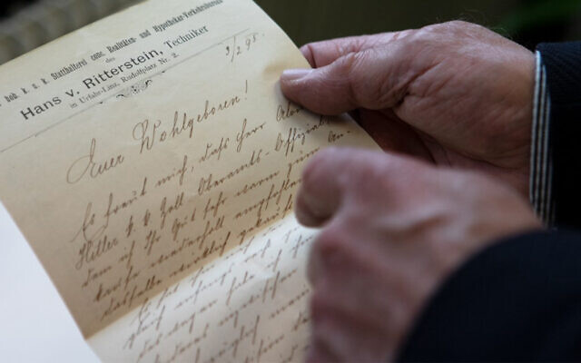 L'historien autrichien Roman Sandgruber tient une lettre écrite par Alois Hitler adressée au fonctionnaire chargé de l'entretien des routes Josef Radlegger, à Linz, en Autriche, le 3 mars 2021. (Crédit ; ALEX HALADA / AFP)