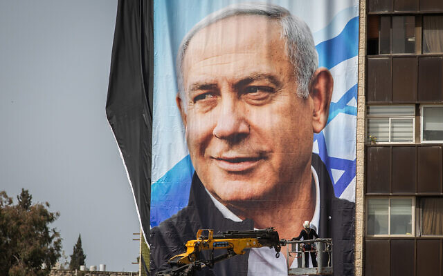 Des employés israéliens accrochent de grandes affiches de la campagne électorale du parti Likud, dans le cadre de la campagne électorale du Likud, à Jérusalem, le 10 mars 2021. (Yonatan Sindel/Flash90) Des employés israéliens accrochent de grandes affiches de la campagne électorale du parti Likud, dans le cadre de la campagne électorale du Likud, à Jérusalem, le 10 mars 2021. (Yonatan Sindel/Flash90)