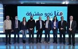 Le dirigeant du parti Maan, Ahmad Darawsheh, se tient au milieu d'un groupe de politiciens de la Liste arabe unie devant un slogan déclarant l'unité des partis. (Autorisation : Maan)