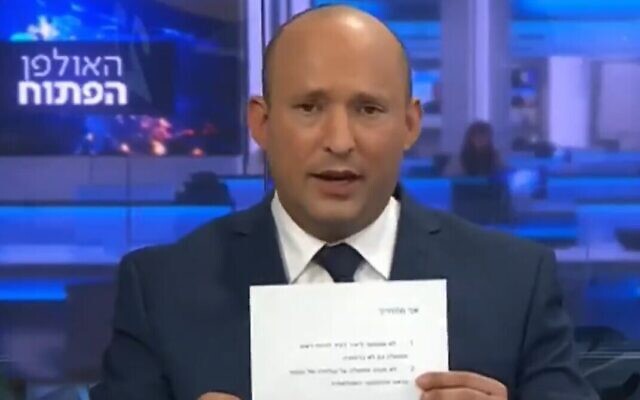 Naftali Bennett montre une promesse signée de ne jamais servir dans un gouvernement dirigé par Yair Lapid, le 21 mars 2021. (Crédit : capture d'écran/Vingtième chaîne) Naftali Bennett montre une promesse signée de ne jamais servir dans un gouvernement dirigé par Yair Lapid, le 21 mars 2021. (Crédit : capture d'écran/Vingtième chaîne)