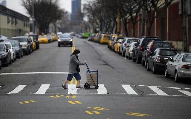 Une femme portant un masque pousse un caddie en traversant une rue du Queens, le 30 mars 2019 à New York. (Johannes EISELE / AFP) Une femme portant un masque pousse un caddie en traversant une rue du Queens, le 30 mars 2019 à New York. (Johannes EISELE / AFP)