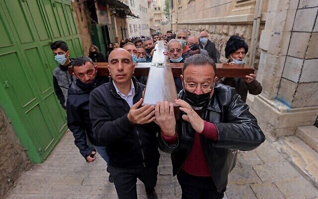 Des fidèles chrétiens portant une croix de bois arrivent à l'église du Saint-Sépulcre, lors de la procession du Vendredi Saint le long de la Via Dolorosa dans la Vieille Ville de Jérusalem, le 2 avril 2021. (Emmanuel DUNAND / AFP)