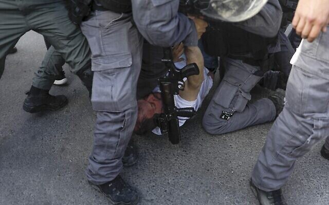 Des policiers israéliens arrêtent le député Ofer Cassif, un membre juif de l'alliance électorale à prédominance arabe Liste arabe unie, lors d'une manifestation dans le quartier de Sheikh Jarrah à Jérusalem, le 9 avril 2021. (AHMAD GHARABLI / AFP)