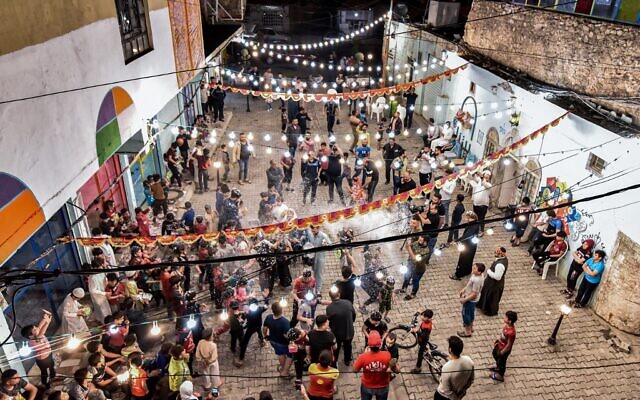 Des enfants jouent avec un bidon de neige artificielle lors d'une fête de rue organisée par une ONG culturelle locale dans la vieille ville de Mossoul, dans le nord de l'Irak, le 13 avril 2021, lors de la première nuit du mois de jeûne sacré musulman du Ramadan. (Crédit : Zaid AL-OBEIDI / AFP)