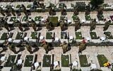 Des soldates israéliennes effectuant des saluts près de tombes au cimetière militaire de Kiryat Shaul, à Tel Aviv, à l'occasion de Yom HaZikaron, le 14 avril 2021. (Crédit : JACK GUEZ / AFP)