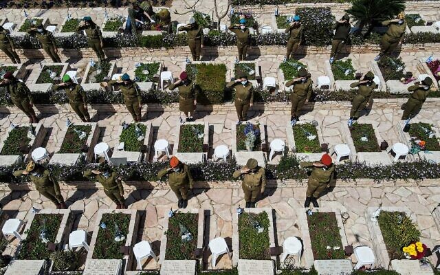 Des soldates israéliennes effectuant des saluts près de tombes au cimetière militaire de Kiryat Shaul, à Tel Aviv, à l'occasion de Yom HaZikaron, le 14 avril 2021. (Crédit : JACK GUEZ / AFP) Des soldates israéliennes effectuant des saluts près de tombes au cimetière militaire de Kiryat Shaul, à Tel Aviv, à l'occasion de Yom HaZikaron, le 14 avril 2021. (Crédit : JACK GUEZ / AFP)