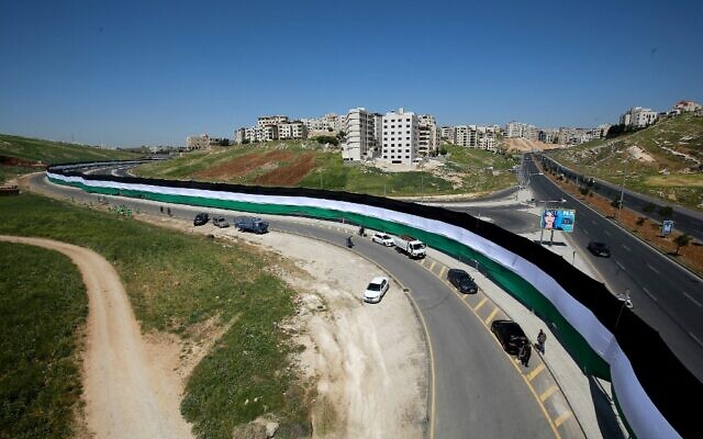 Une photo montre des ouvriers de la municipalité d'Amman installant un drapeau jordanien de 2132 mètres de long visant à battre le record du monde Guinness du plus long drapeau du monde, le 15 avril 2021 dans la capitale jordanienne. (Crédit : Khalil MAZRAAWI / AFP)