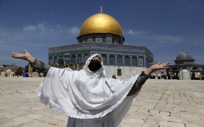 Une femme palestinienne lève les bras pour la première lors de la première prière du vendredi du Ramadan aux abords du Dôme des roches, sur le mont du Temple de Jérusalem, le 26 avril 2021. (Crédit : Ahmad GHARABLI / AFP)
