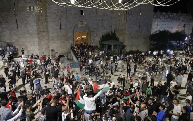 Des manifestants palestiniens brandissent des drapeaux nationaux durant un rassemblement près de la porte de Damas dans la vieille ville de Jérusalem, le 25 avril 2021. (Crédit : Ahmad GHARABLI / AFP)