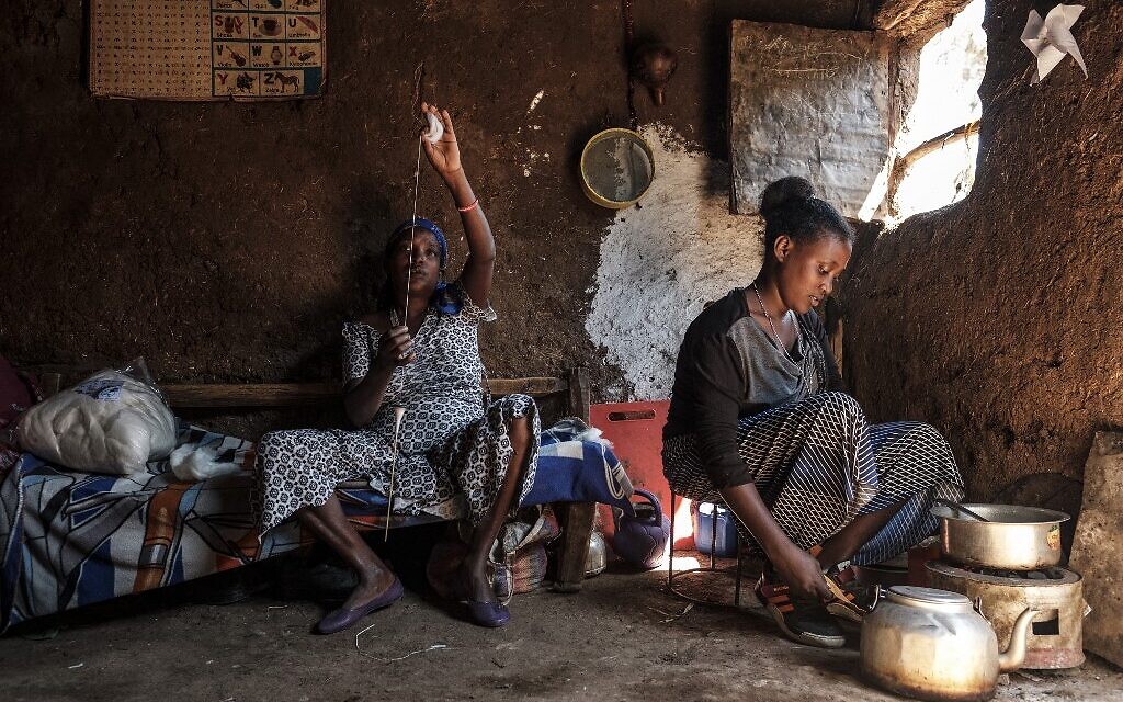 Une femme membre de la communauté juive éthiopienne tricote tandis qu'une autre cuisine, dans la ville de Gondar, en Ethiopie, le 27 octobre 2020. (Crédit : EDUARDO SOTERAS / AFP)