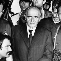 Des policiers français conduisent Klaus Barbie, au centre, menotté, hors de la salle d'audience de Lyon, après avoir été condamné le 4 juillet 1987 pour crimes contre l'humanité alors qu'il était chef de la Gestapo dans cette ville. (Crédit : AP)