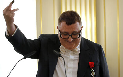 Le créateur de mode israélo-américain Alber Elbaz montre un dé à coudre qui appartenait autrefois à une survivante de la Shoah et qui lui a été donné par la fille celle-ci alors qu'il prononce un discours après avoir reçu le grade d'Officier de la Légion d'Honneur au ministère de la Culture, à Paris, le 3 octobre 2016. Elbaz a déclaré qu'il gardait toujours le dé avec lui. (Crédit : AP / François Mori)