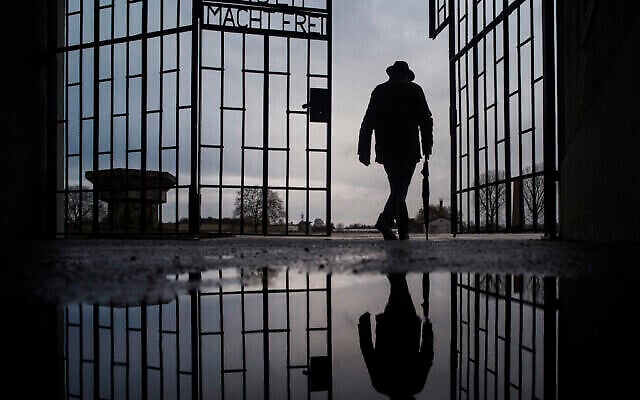 Un homme franchit la porte du camp de la mort nazi de Sachsenhausen avec la phrase "Arbeit macht frei" (le travail rend libre) à Oranienburg, en Allemagne, lors de la Journée internationale de commémoration de la Shoah, le 27 janvier 2019. (Markus Schreiber/AP)