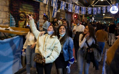Des femmes israéliennes fêtent Yom HaAtsmaout au marché Mahane Yehuda à Jérusalem, après plus d'un an de restrictions liées au coronavirus, le 14 avril 2021. (Crédit : AP Photo/Maya Alleruzzo)