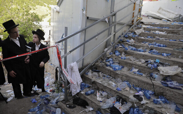 Des Juifs ultra-orthodoxes contemplent le site d'une bousculade mortelle lors des festivités de Lag BaOmer au Mont Meron, dans le nord d'Israël, le 30 avril 2021. (Crédit : AP Photo/Sebastian Scheiner)