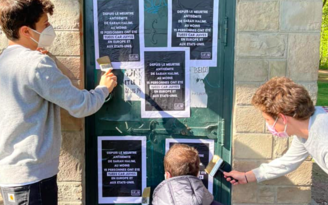 Des jeunes de l’UEJB collent des affiches contre l’antisémitisme, à Bruxelles, le 25 avril 2021. (Crédit : UEJB)