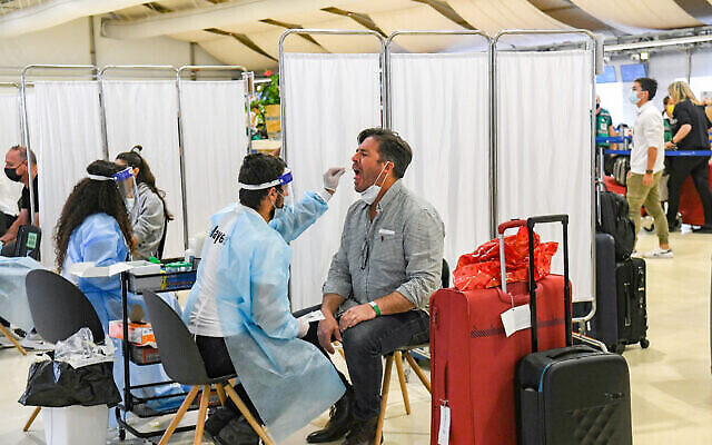 Des assistants médicaux testent des passagers pour la COVID-19 à l'aéroport international Ben Gurion près de Tel Aviv, le 8 mars 2021. (Flash90) Des assistants médicaux testent des passagers pour la COVID-19 à l'aéroport international Ben Gurion près de Tel Aviv, le 8 mars 2021. (Flash90)