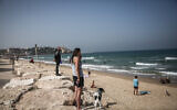 Des gens immobiles sur la plage de Tel Aviv, pendant la sirène de deux minutes à travers Israël marquant le jour du souvenir de la Shoah, le 8 avril 2021. (Crédit : Miriam Alster / Flash90)