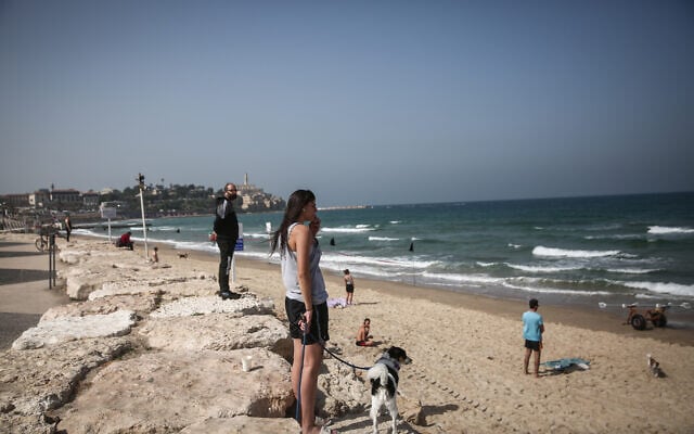 Des gens immobiles sur la plage de Tel Aviv, pendant la sirène de deux minutes à travers Israël marquant le jour du souvenir de la Shoah, le 8 avril 2021. (Crédit : Miriam Alster / Flash90)