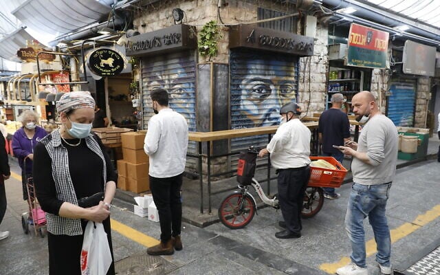 Des gens immobiles au marché Mahane Yehuda à Jérusalem, pendant la sirène de deux minutes à travers Israël marquant le jour du souvenir de la Shoah, le 8 avril 2021. (Crédit : Olivier Fitoussi / Flash90)