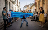 Un Israélien coupe un masque géant pour fêter la fin de l'obligation du port du masque à Jérusalem, le 18 avril 2021. (Crédit :  Yonatan Sindel/Flash90)