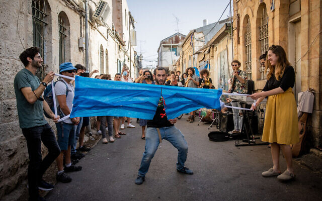 Un Israélien coupe un masque géant pour fêter la fin de l'obligation du port du masque à Jérusalem, le 18 avril 2021. (Crédit : Yonatan Sindel/Flash90) Un Israélien coupe un masque géant pour fêter la fin de l'obligation du port du masque à Jérusalem, le 18 avril 2021. (Crédit : Yonatan Sindel/Flash90)