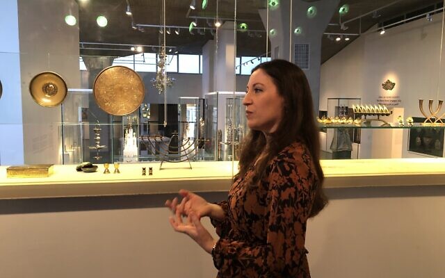 La conservatrice du musée d'Israël Sharon Weiser-Ferguson dans l'aile de l'Art et de la Vie juive, avec certains objets qui ont été donnés par les parents de Yadin Tanenbaum, mort pendant la guerre de Yom Kippour, en mémoire de leur fils. (Crédit : Jessica Steinberg/Times of Israel)