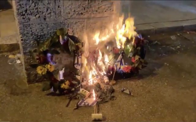 Des couronnes de fleurs et des drapeaux qui se trouvaient sur des tombes des soldats de Tsahal pour Yom HaZikaron, incendiés le 14 avril 2021. (Capture d'écran : Kan News/ Twitter) Des couronnes de fleurs et des drapeaux qui se trouvaient sur des tombes des soldats de Tsahal pour Yom HaZikaron, incendiés le 14 avril 2021. (Capture d'écran : Kan News/ Twitter)