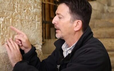 Amit Reem, de l'Autorité israélienne des Antiquités, examine des croix gravées dans un mur de l'Église du Saint-Sépulcre à Jérusalem. (Capture d'écran vidéo)