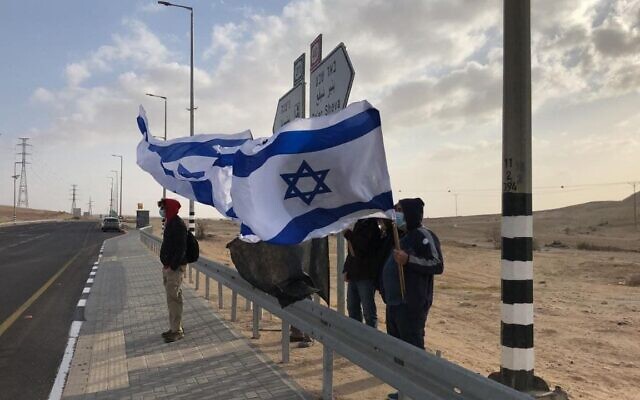 Des Israéliens manifestent contre le Premier ministre Benjamin Netanyahu à un carrefour situé aux abords de Tlalim, dans le sud d'Israël, le 10 avril 2021. (Autorisation : Drapeaux noirs)
