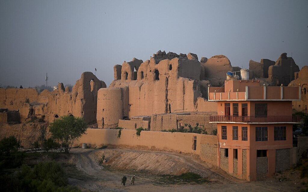 Sur cette photo prise le 27 mars 2021, des hommes marchent le long d'un sentier près d'un ancien palais où vivent des familles déplacées, au Qal-e-Kohna, un site historique de Lashkar Gah, la capitale de la province de Helmand. Autrefois résidence d'hiver des sultans d'illustres dynasties islamiques, les ruines d'une cité royale millénaire du sud de l'Afghanistan sont devenues le lieu de résidence de centaines de personnes qui ont fui les affrontements avec les talibans. (Crédit : WAKIL KOHSAR / AFP) Sur cette photo prise le 27 mars 2021, des hommes marchent le long d'un sentier près d'un ancien palais où vivent des familles déplacées, au Qal-e-Kohna, un site historique de Lashkar Gah, la capitale de la province de Helmand. Autrefois résidence d'hiver des sultans d'illustres dynasties islamiques, les ruines d'une cité royale millénaire du sud de l'Afghanistan sont devenues le lieu de résidence de centaines de personnes qui ont fui les affrontements avec les talibans. (Crédit : WAKIL KOHSAR / AFP)