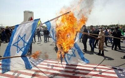 Les Iraniens mettent le feu à des drapeaux israéliens en piétinant des drapeaux américains pendant un rassemblement de la journée al-Quds dans la capitale de Téhéran, place Azadi (Liberté), le 7 mai 2021. (Crédit :  STR / AFP)
