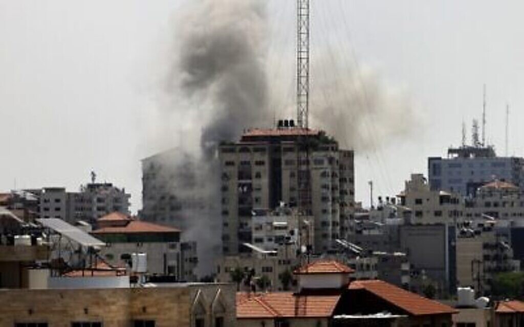De la fumée s'élève d'un bâtiment frappé par les Israéliens à Gaza City, parmi les tirs de roquette de la bande, le 11 mai 2021. (Crédit : MOHAMMED ABED / AFP)