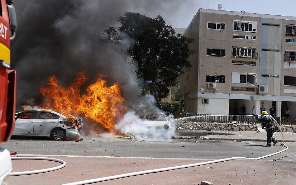 Un pompier israélien éteint un véhicule en feu après qu'une roquette lancée depuis la bande de Gaza, dirigée par le Hamas, a frappé la ville d'Ashkelon, dans le sud d'Israël, le 11 mai 2021. (Crédit : (JACK GUEZ / AFP)