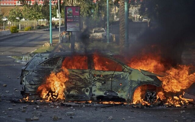 Une voiture de police israélienne en feu après une émeute d'Arabes israéliens à Lod, le 12 mai 2021. (Crédit : Ahmad GHARABLI / AFP) Une voiture de police israélienne en feu après une émeute d'Arabes israéliens à Lod, le 12 mai 2021. (Crédit : Ahmad GHARABLI / AFP)