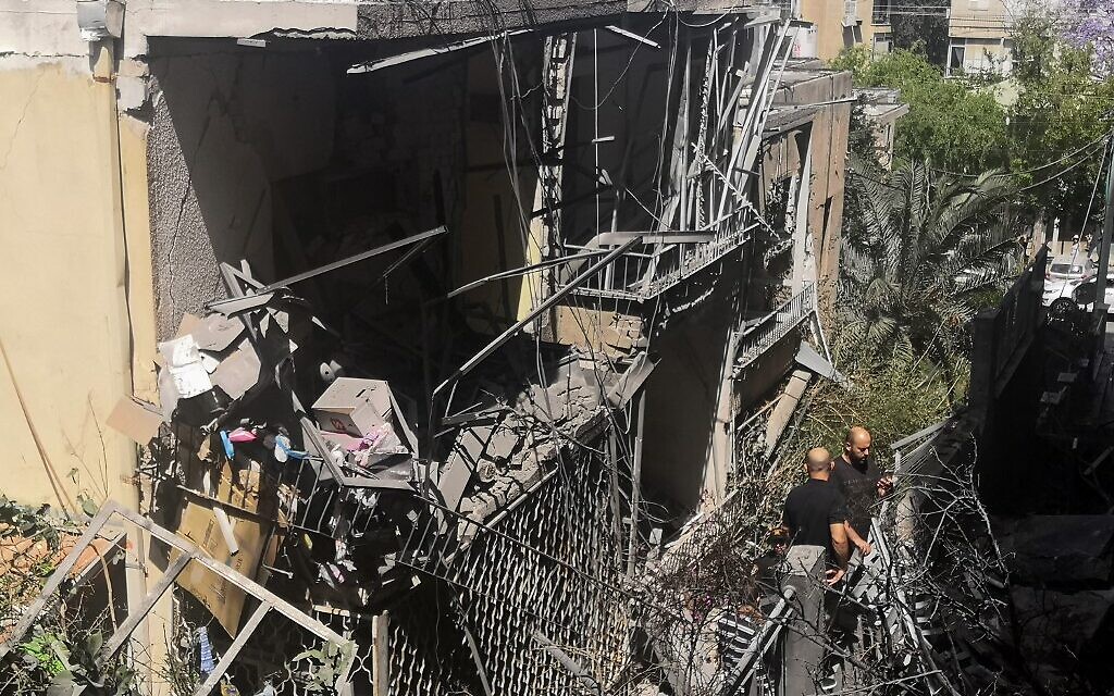 Des résidents israéliens inspectent une maison endommagée dans la banlieue de Tel Aviv, à Givatayim, le 12 mai 2021, après une frappe nocturne de roquettes, la première de l'histoire du quartier. (Crédit : Alexandra VARDI / AFP)