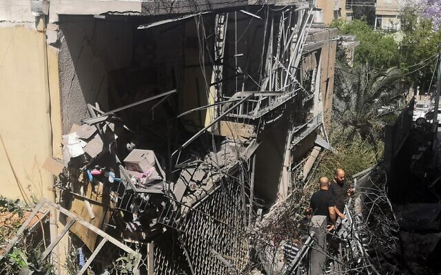 Des résidents israéliens inspectent une maison endommagée dans la banlieue de Tel Aviv, à Givatayim, le 12 mai 2021, après une frappe nocturne de roquettes, la première de l'histoire du quartier. (Crédit : Alexandra VARDI / AFP)