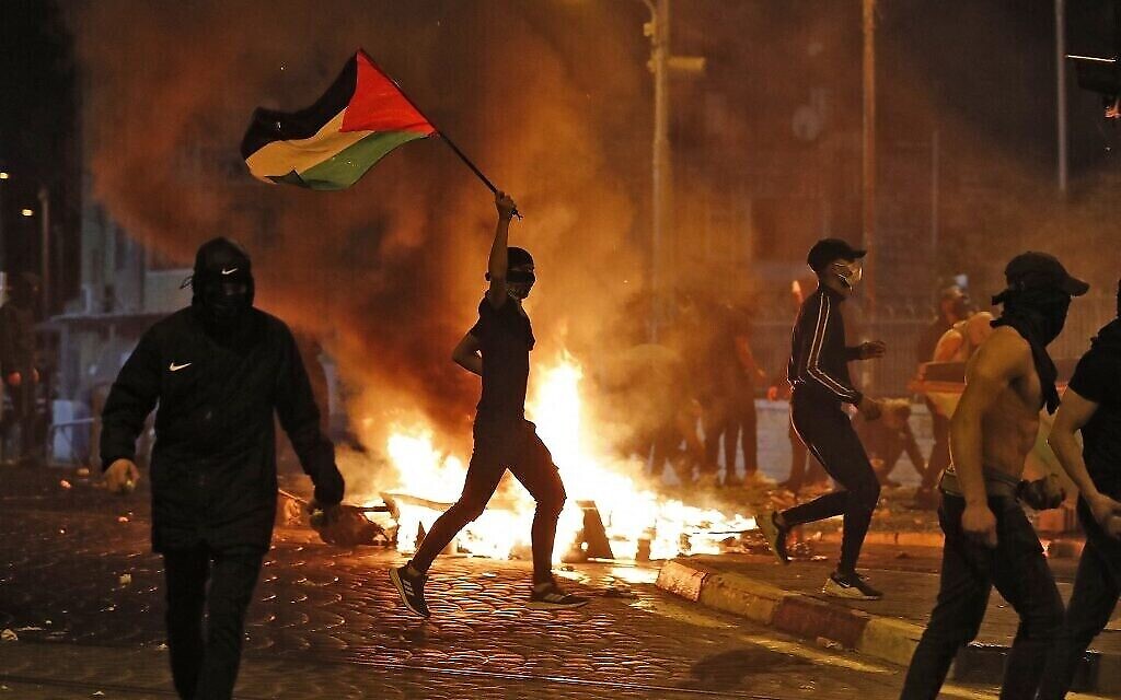 Des émeutiers palestiniens lancent des pierres lors d'affrontements avec les forces israéliennes dans le quartier palestinien de Shuafat à Jérusalem-Est le 14 mai 2021. (Crédit : Ahmad GHARABLI / AFP)