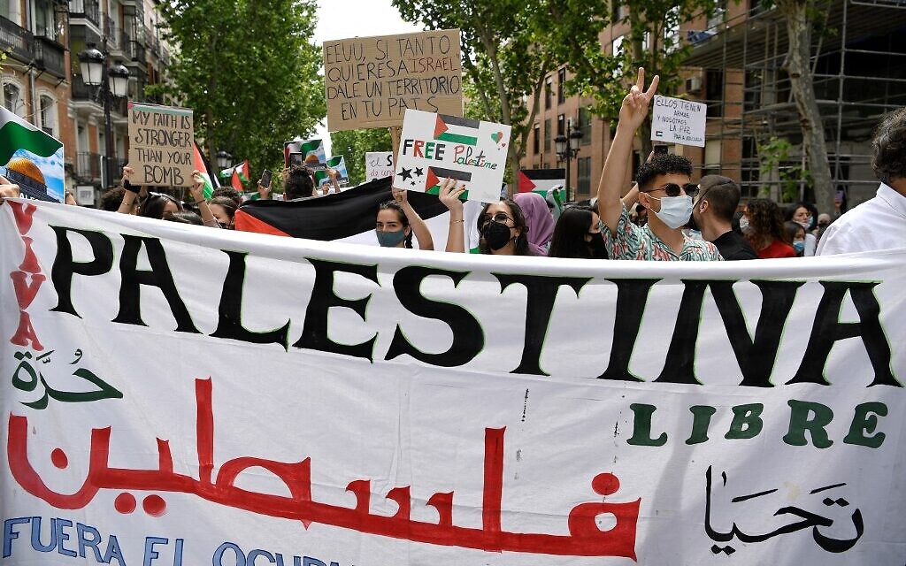 Les gens tiennent un grand tissu où l'on peut lire en partie "Palestina" alors qu'ils participent à une manifestation marquant le 73e anniversaire de la "Naqba", à Madrid le 15 mai 2021. (Crédit : GABRIEL BOUYS / AFP)