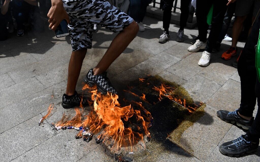 Des manifestants brûlent un drapeau américain lors d'une manifestation marquant le 73e anniversaire de la "Naqba" (catastrophe) à Madrid le 15 mai 2021. (Crédit : GABRIEL BOUYS / AFP)