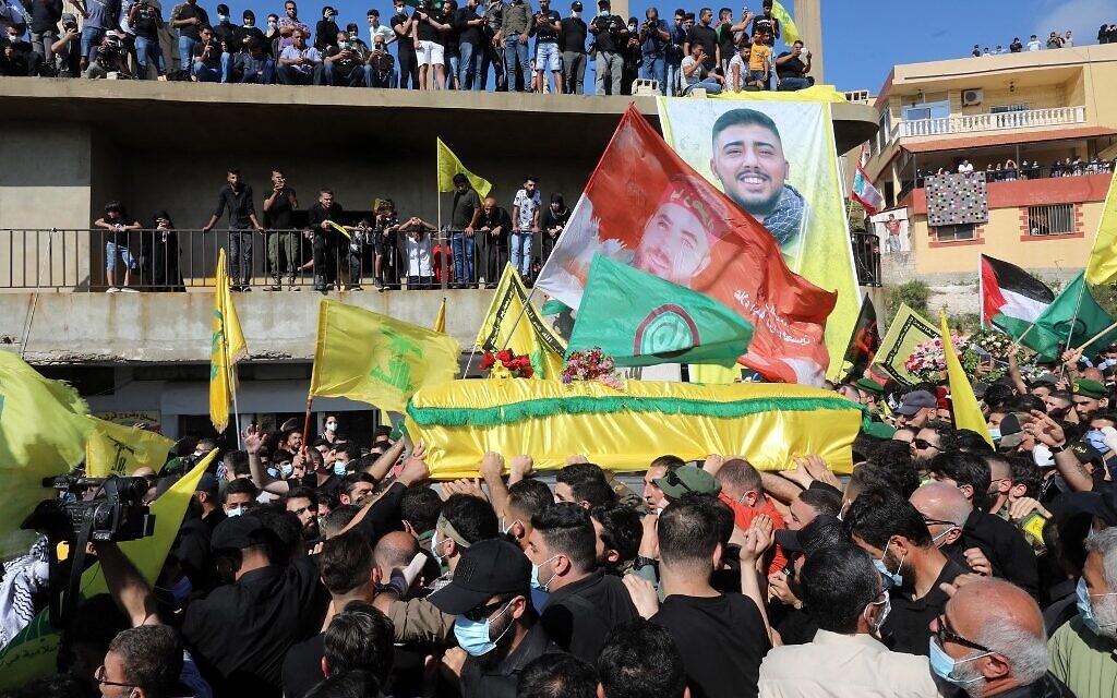 Des personnes en deuil portent le cercueil de Mohamad Kassem Tahan, membre du mouvement Hezbollah soutenu par l'Iran, tué un jour plus tôt à la frontière avec le Liban, lors de ses funérailles dans le sud du Liban village d'Adloun, le 15 mai 2021. - Des centaines de personnes brandissant des drapeaux palestiniens et les couleurs jaunes du Hezbollah se sont rassemblées pour les funérailles. (Crédit : Anwar AMRO / AFP)
