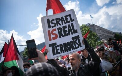 Un manifestant tient une pancarte où l'on peut lire "Israël est un vrai terroriste", le 15 mai 2021 sur la Hermannplatz à Berlin. (Crédit : STEFANIE LOOS / AFP)