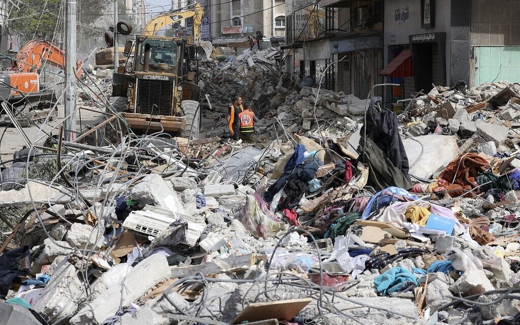 Une excavatrice nettoie les décombres d'un bâtiment détruit dans le quartier résidentiel chic de Rimal, à Gaza, le 16 mai 2021 (Crédit : Mahmud Hams / AFP)
