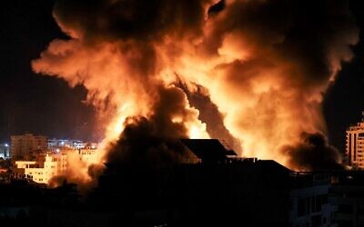 Des explosions éclairent la nuit au-dessus des immeubles de Gaza lors de frappes israéliennes sur l'enclave côtière, avant l'aube, le 18 mai 2021. (Crédit : MAHMUD HAMS / AFP) (Photo by Mahmud hams / AFP)