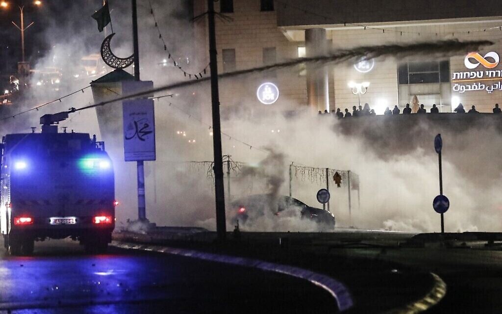 Les forces de sécurité israéliennes aspergeant des émeutiers palestiniens de skunk lors de confrontations dans la ville majoritairement arabe d'Umm al-Fahm, dans le nord d'Israël, le 19 mai 2021. (Crédit : Ahmad Gharabli/AFP)