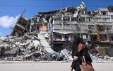 Une Palestinienne passe devant un immeuble détruit dans le quartier commercial d'al-Rimal à Gaza City, suite à une frappe israélienne, après le cessez-le-feu conclu entre Israël et les groupes terroristes palestiniens. (Crédit :Emmanuel Dunand/AFP)