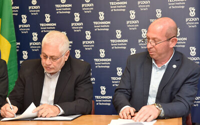 De gauche à droite, le président du Technion, le professeur Uri Sivan, signe l'accord de collaboration avec l'hôpital Israelita Albert Einstein de Sao Paulo, au Brésil, et le professeur Alon Wolf, responsable du développement des ressources, le 6 mai 2021. (Crédit : Sharon Tzur, bureau du porte-parole du Technion)