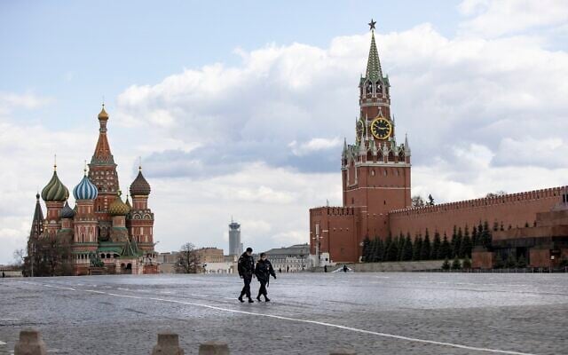 Deux officiers de police patrouillent sur une Place Rouge presque vide, avec la cathédrale Saint-Basile, au centre, et la tour Spasskaya à Moscou, en Russie, le 20 avril 2020. (Crédit : AP Photo/Alexander Zemlianichenko)