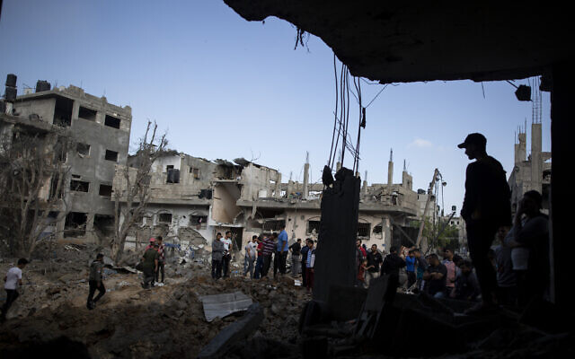 Des Palestiniens inspectent des maisons détruites par les frappes israéliennes nocturnes dans le nord de la bande de Gaza en représailles aux tirs de roquettes sur Israël, le 14 mai 2021. (Crédit : AP Photo/Khalil Hamra)