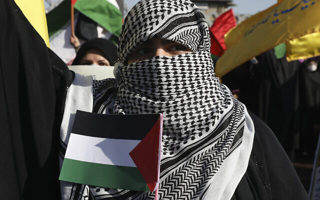Photo d'illustration : Une femme, le visage couvert comme le sont les militants palestiniens et libanais, tient un drapeau propalestinien lors d'un rassemblement à Téhéran, le 19 mai 2021. (Crédit : AP Photo/Vahid Salemi)